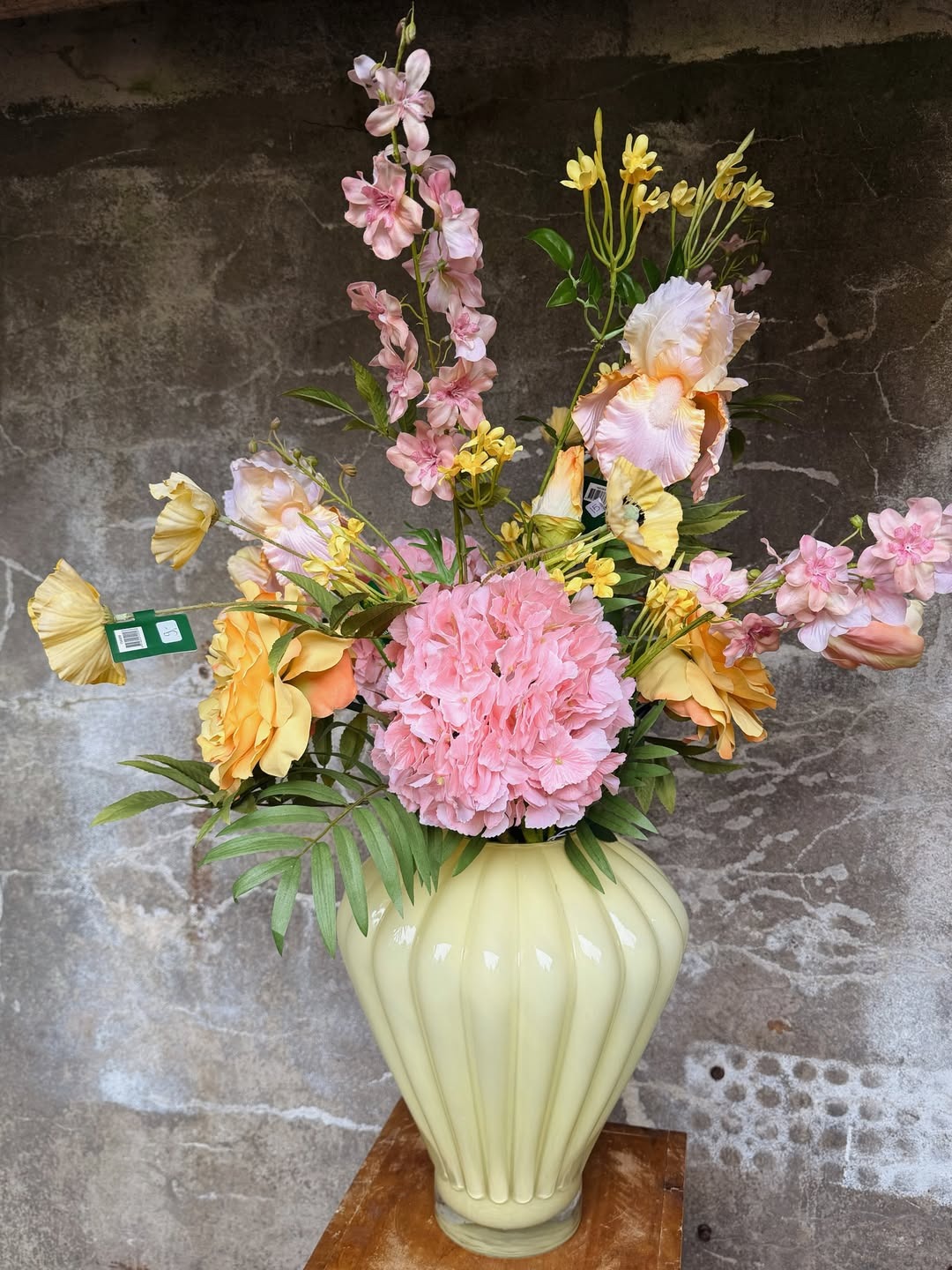 Boeket met hortensia, delphiniums en iris in een lichtgele vaas
